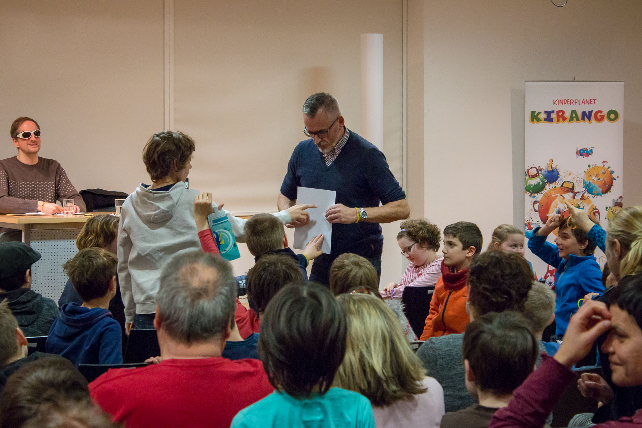 Frank M. Reifenberg zeigt Kinder Text mit Brailleschrift